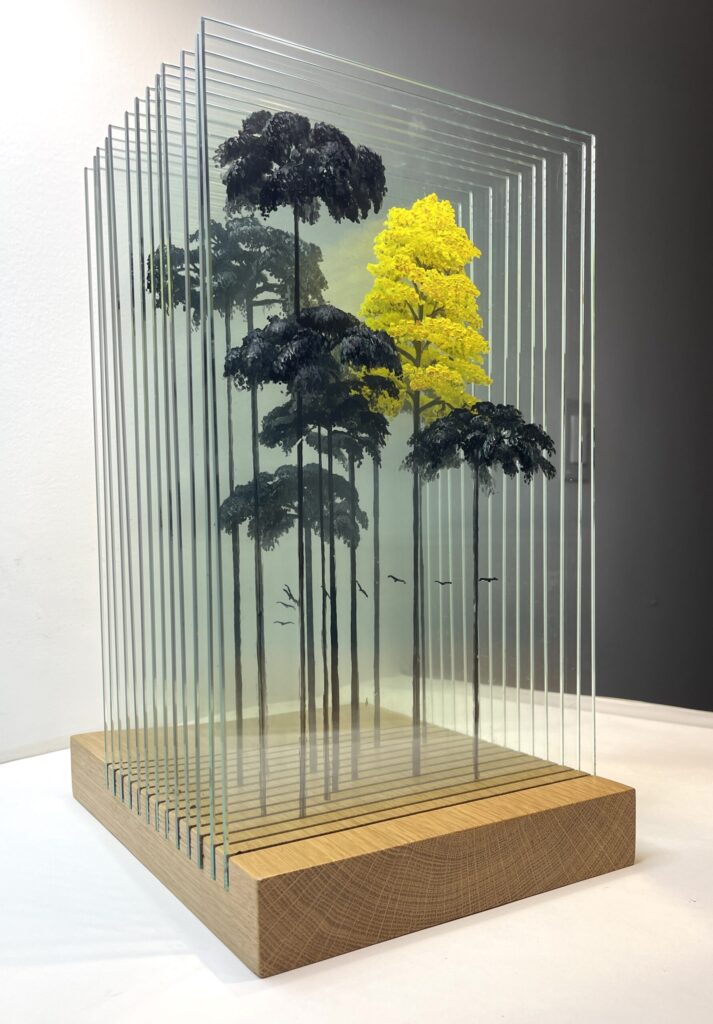 A mixed media sculpture of amazon rainforest trees, in black and yellow, looking like a 3D barcode.
